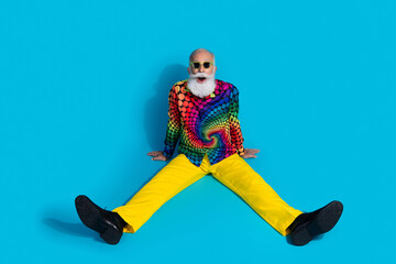 Full size photo of funny stylish aged man sitting floor open mouth isolated on blue color background
