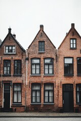 Obraz premium Charming brick houses line a quiet street in a historic European town on a cloudy day, showcasing traditional architecture and inviting character