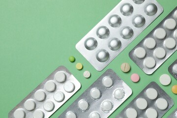 Pills in blister packs on green background, close up