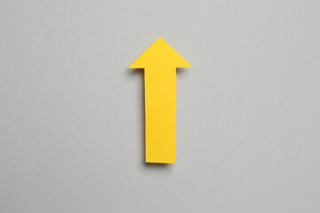 Paper arrow on gray background, top view