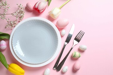 Easter decor concept. Top view photo of colorful eggs in a plate with knife and fork on pastel background
