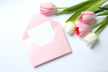 Top view photo of open pink envelope with paper card and tulip flowers on white background with empty space