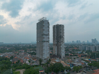 Obraz premium Stunning aerial shot of two modern high-rise buildings under construction against a cloudy sky. Perfect for real estate, architecture, and urban development projects.