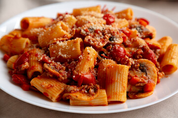 Homemade Italian Sausage and Mushroom Ragu Rigatoni Pasta with Cheese on a Plate, side view. Close-up.