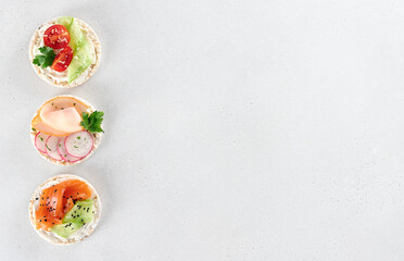 Set rice cakes, sandwiches with fresh vegetables, salmon, ham, protein. Healthy, low-calorie, diet snacks. Copy space.