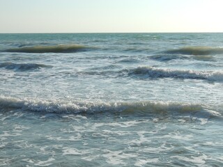 beautiful sea waves on a sunny day seen from the beach, sea surface texture with foamy tide crest as a natural background, sea tides as a natural phenomenon
