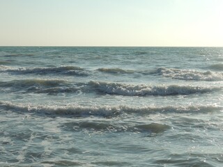 the tide of the sea or ocean in the soft rolling of a foamy wave on a rocky beach on a sunny clear day, a beautiful deserted seascape with a smooth surf, silver-blue waves running onto a pebble shore