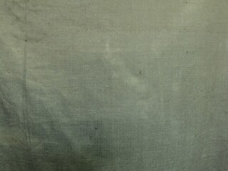 texture of rough tarpaulin fabric dirty green color close-up, fabric background of awning or camouflage macro view, old wrinkled dirty shabby canvas as an empty backdrop