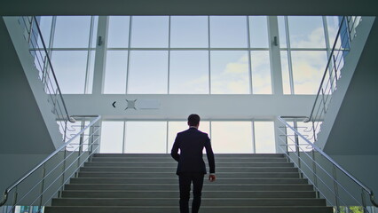 Confident employee running upstairs office back view. Determined businessman