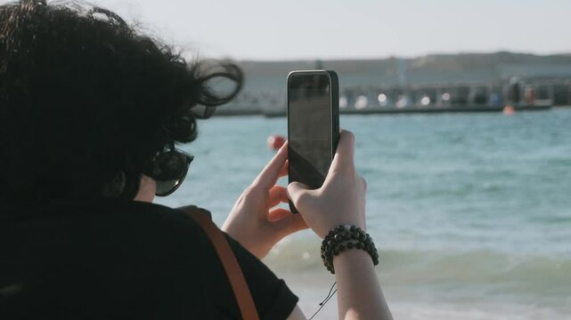 Girl filming the sea 
