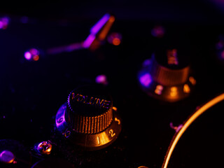 Electric guitar close up. Volume knob. Musical instrument details. Concert color contrast lighting. Six-string guitar during performance. Bright colors on dark background. Cinematic light. Copy space