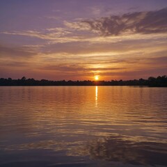 Obraz premium The sun is setting, casting a golden hue across the tranquil water below, with the sky reflecting soft pink and purple tones.