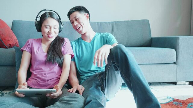 A joyful couple engaged in a fun gaming session at home, wearing headphones and sharing laughter. Their relaxed atmosphere shows the importance of connection and leisure.