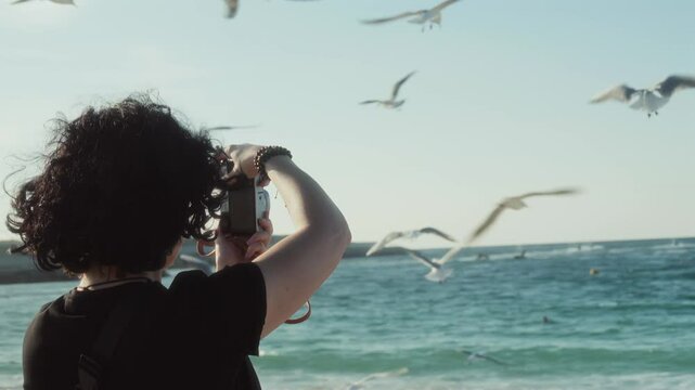 girl taking photos of seagulls