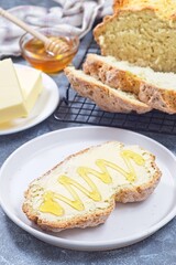 Freshly baked white Irish soda bread with butter and honey served on a plate, vertical