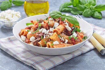 Rigatoni alla Norma pasta with eggplant and tomato, served with basil and ricotta salata, horizontal