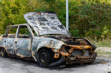 Burned car wreck abandoned on roadside in nature