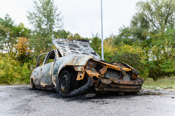 Burned car wreck abandoned on roadside in nature