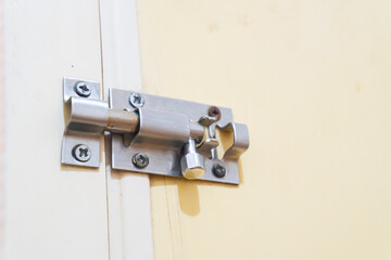 Manual stainless steel door latch lock with metal pin and screws installed in a PVC door inside a house. The concept of security.