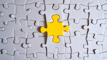 A single yellow puzzle piece fits among many white ones