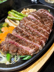 Close up of medium rare rib eye steak with grilled vegetable.
