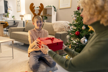 Joyful Child Receiving a Gift During Christmas Celebration at Home