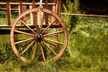 Vintage wooden cart wheel resting in lush green grass at a serene countryside location