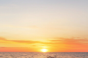 Fototapeta premium stunning sunset over ocean, showcasing gradient of fiery orange fading into golden yellow, creating serene and peaceful atmosphere