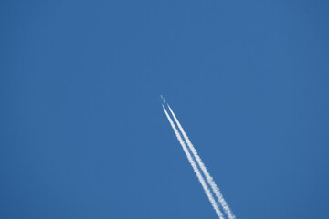 Airplane in the blue sky with trace of a passenger plane.