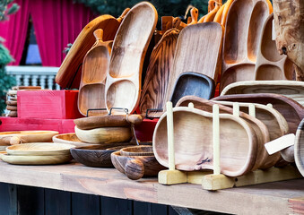 market stall showcasing variety of handcrafted wooden kitchenware and tableware, cutting boards, serving trays, bowls, and plates, made from natural wood with unique grains and textures