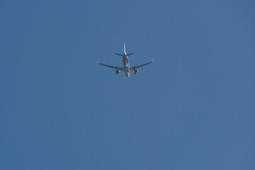 Jet airplane flying overhead in clear blue sky. Airplane in the blue sky.