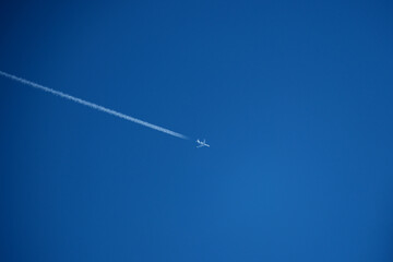 Airplane in the blue sky with trace of a passenger plane.