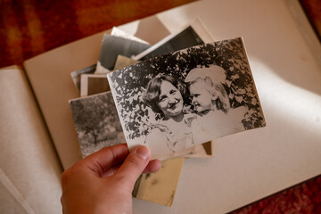 Female hand is holding black and white old photo of her grandmother with her daughter. Vintage photo album with photos. Family and life values concept. Mother and her little girl