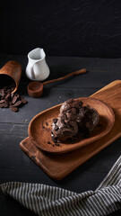 Indulgent chocolate ice cream topped with crushed cookies is beautifully arranged on a wooden plate alongside a small jug of milk