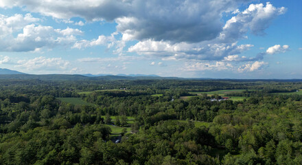 Fototapeta premium view of catskill mountains at sunset (wide angle aerial mountain vista in catskills hudson valley slide mountain wilderness hiking area) dramatic huge puffy clouds sky cloud formation farm rural area