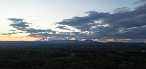 view of catskill mountains at sunset (wide angle aerial mountain vista in catskills hudson valley slide mountain wilderness hiking area) dramatic huge puffy clouds sky cloud formation farm rural area