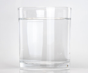 Clear glass filled with water on a plain background
