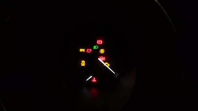A vehicle dashboard is showcasing multiple illuminated warning lights glowing brightly in the darkness, signaling various potential issues that may require immediate attention and care