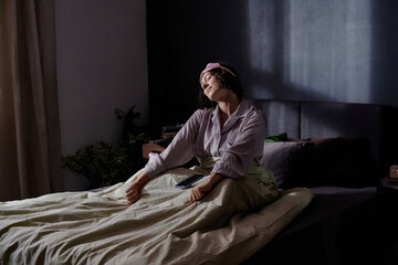 Wide shot of smiling and happy woman stretching her body after good all night sleep, she enjoying morning routine while sun warming her skin with first rays