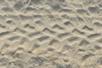 Tire tracks imprinted on sandy terrain. Pattern of vehicle tread marks on dry sand. Off-road vehicle tracks in a sandy environment.