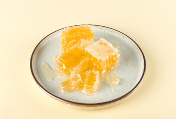 Golden organic honeycomb onplate on yellow background. Beekeeping, ecologically natural food concept. Sugar replacement.