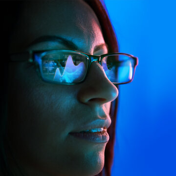 Close-up of woman wearing glasses reflecting bar charts and financial analytics, symbolizing technology and business decision-making. Concept of business, finance, investment, planning