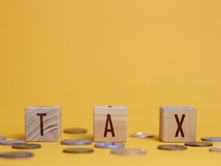 Tax. Wooden cubes with letters forming a word. Photo concept with the theme of finance and taxation with wooden cubes as props with a yellow background.
