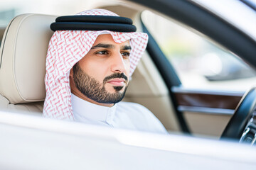 A man wearing a white shirt and a red and white scarf sits in a car