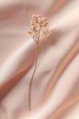 Delicate gold-toned flower sprig on a soft blush pink fabric. Elegant and minimalist aesthetic.