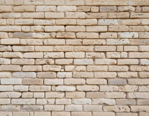 Fototapeta premium Outdoor aged rustic texture of sunbleached bricks in light beige and cream tones seamless background urban environment detailed view for visual appeal