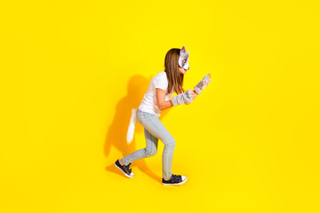 Young girl in animal costume playfully portraying a cat against a vibrant yellow background