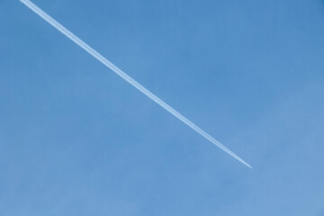 aereo di linea che vola lontano, in alto, nel cielo sereno e lascia la scia di condensa