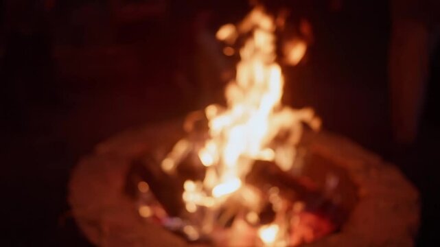 Out of focus blurred blur of fire flames in fire pit in slo mo slow motion outdoors at night during campout and celebration ceremony in darkness with bright red flame for background plate