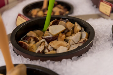 Colorful bowls of gourmet mushrooms are arranged neatly on ice, making a tempting display at a food market event. Copy space. Soft focus.